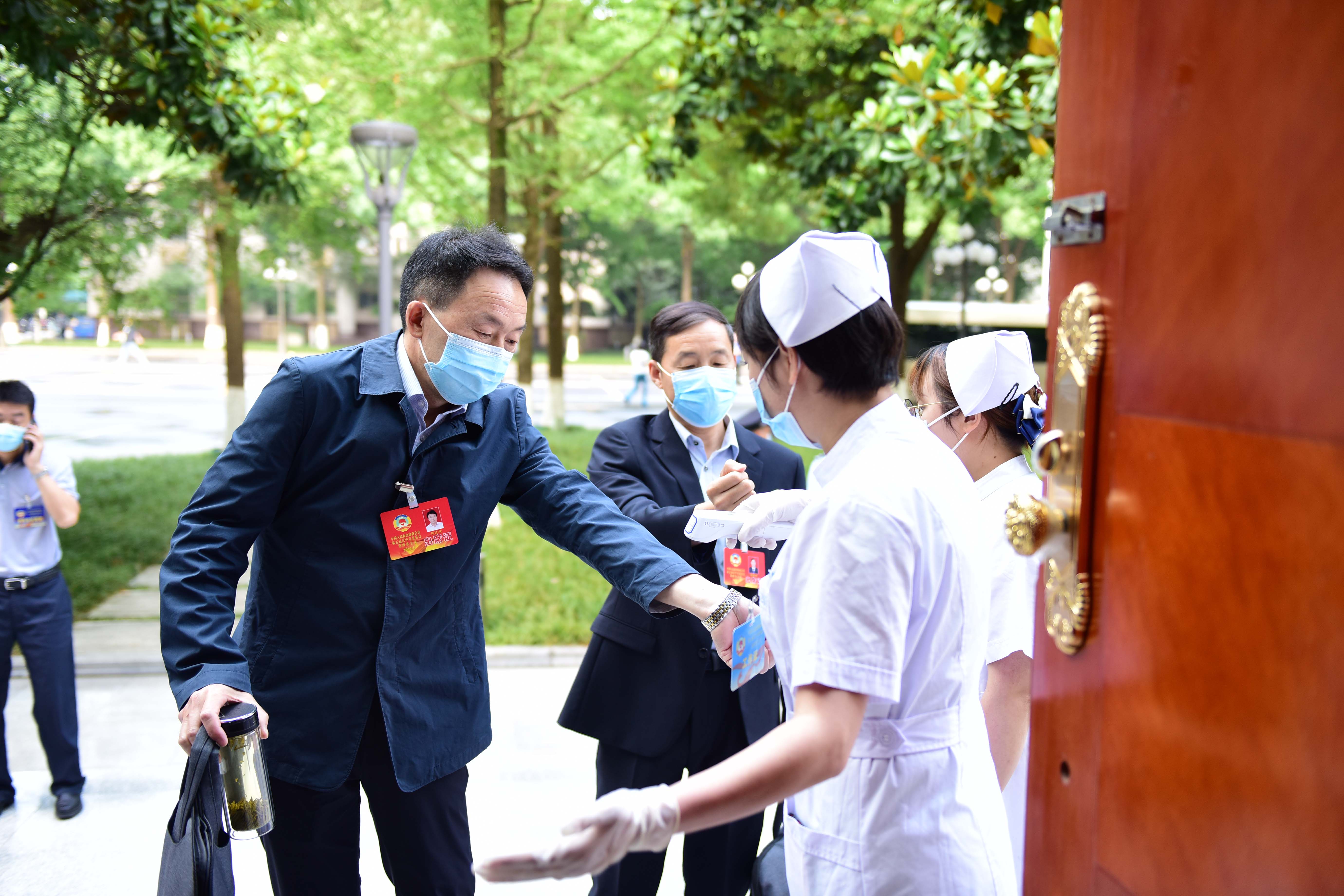 参加市政协五届四次会议的委员接受体温检测后步入会场。 本报记者 汤江 摄。